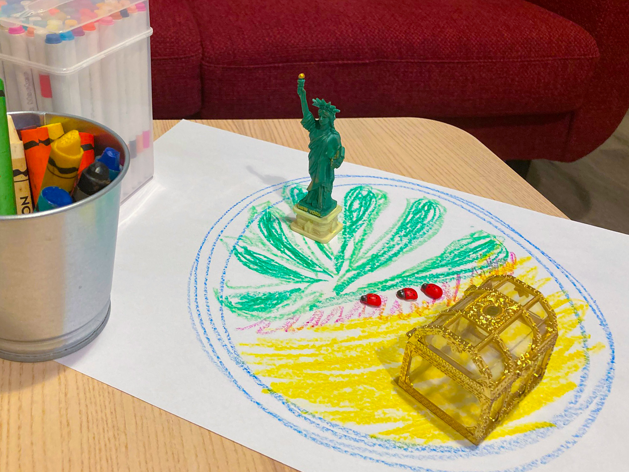 Expressive therapy tools on a table, including crayons, drawings, figurines and a toy treasure chest
